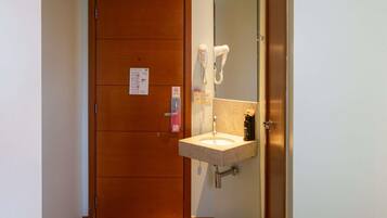A hotel bathroom with a wooden door, a sink with a towel rack, and a mirror.