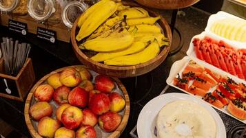 Diversas frutas como bananas, maçãs, laranjas e mamão dispostas sobre um balcão.
