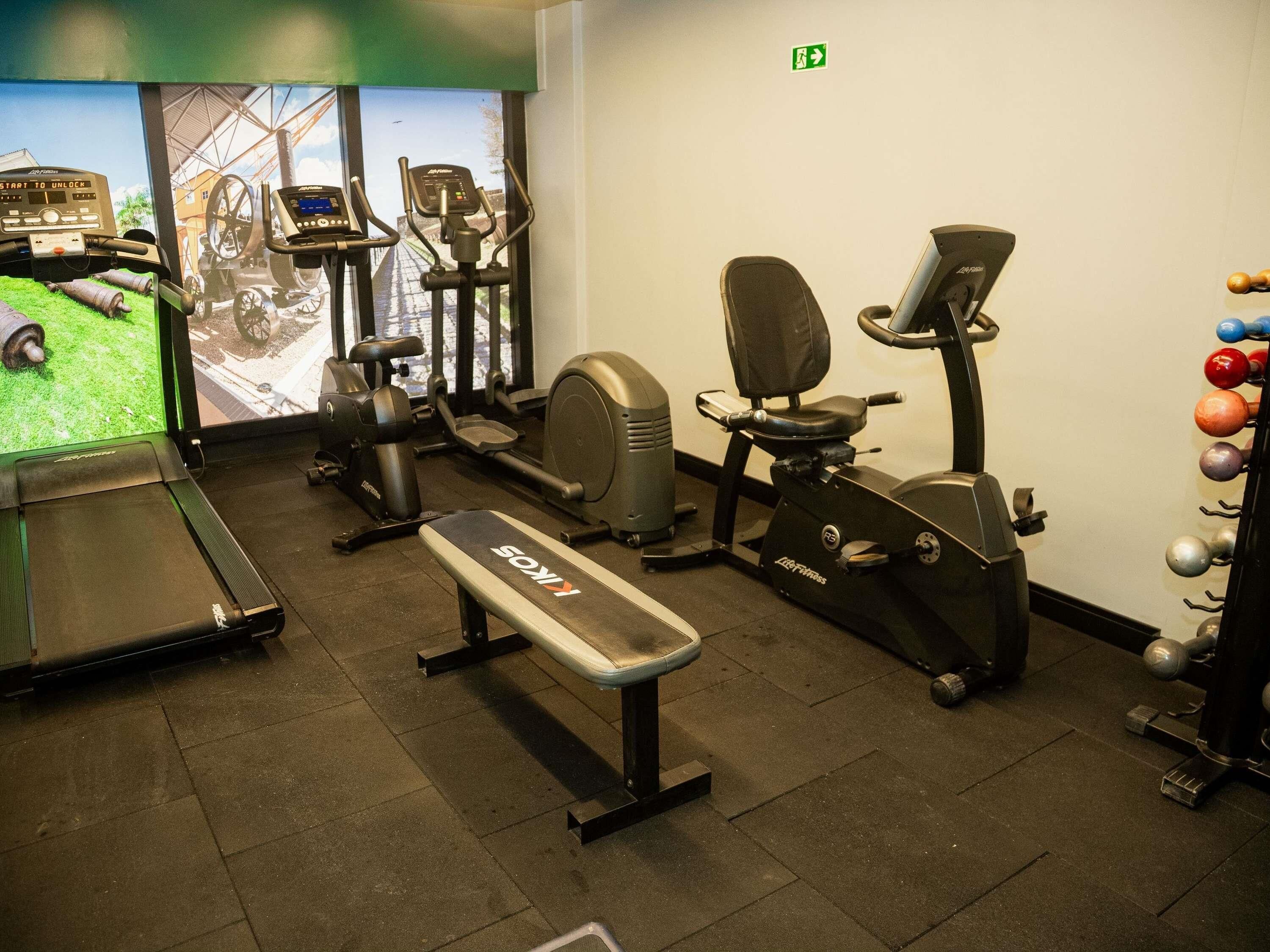 A gym with cardio machines, a treadmill, and a bench.