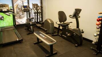 A gym with cardio machines, a treadmill, and a bench.