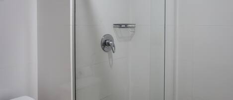 A bathroom with a glass-enclosed shower, a toilet, and a towel rack.