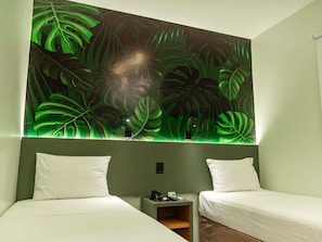 Una habitación con dos camas, una mesita de noche y una pared con un estampado de hojas tropicales.