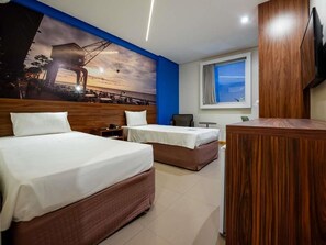 A hotel room with two beds, a TV, a window, and a mural of a sunset. - Ibis Styles Belém Hangar (Belém)