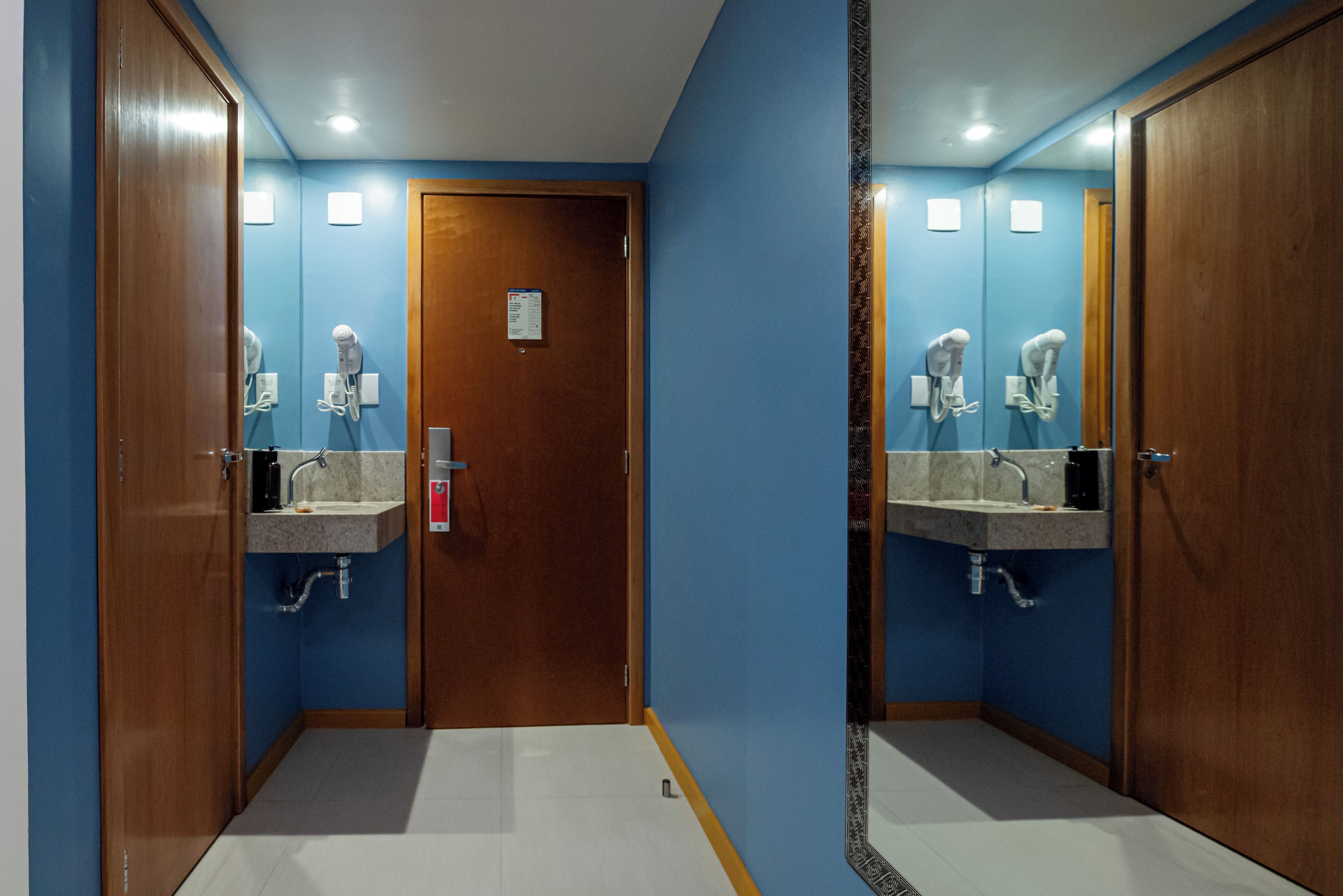 A bathroom with two sinks, a wooden door, and a mirror.