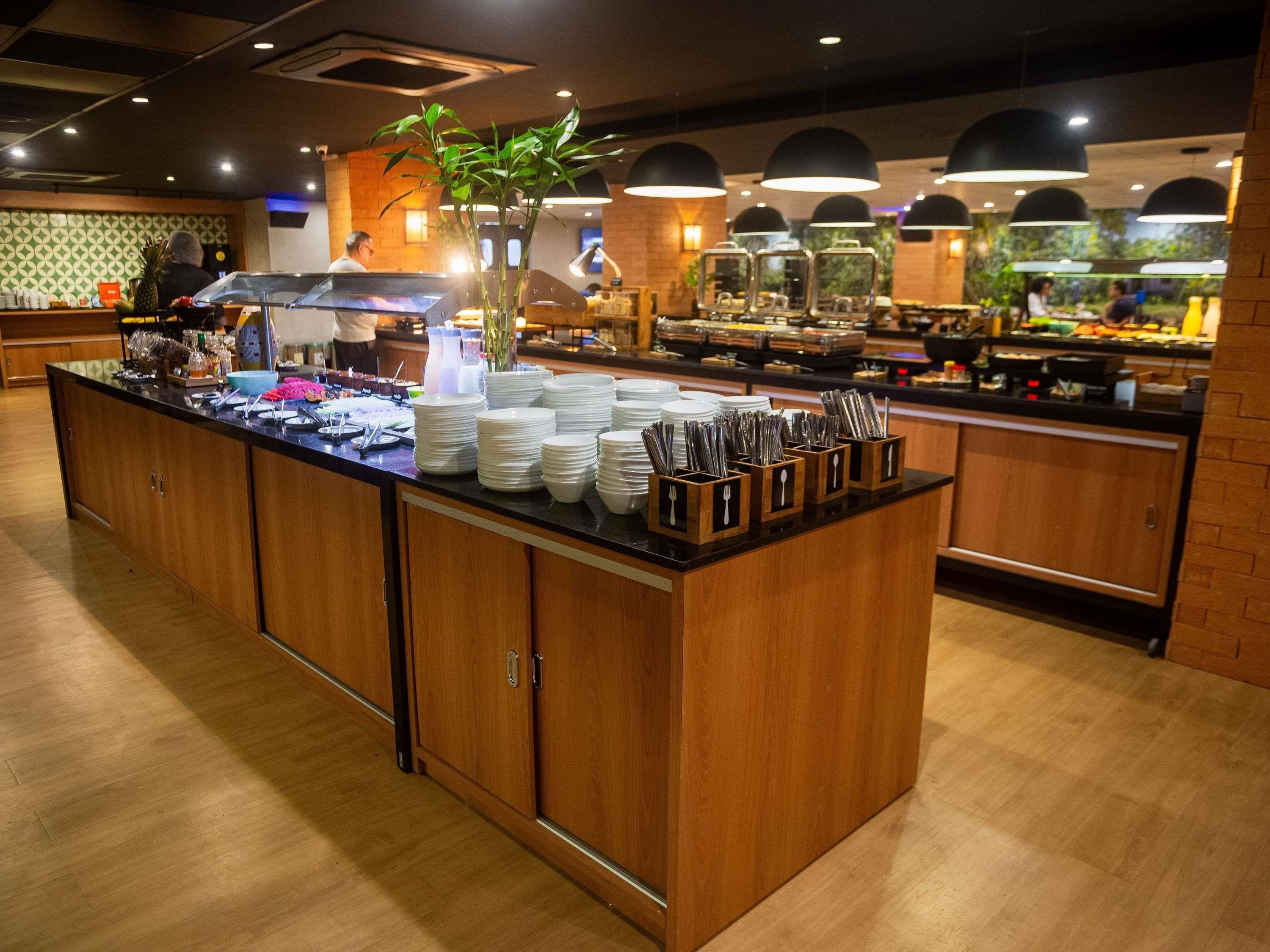 En buffé med flera serveringsstationer, ett stort utbud av mat och en centralt placerad växt.