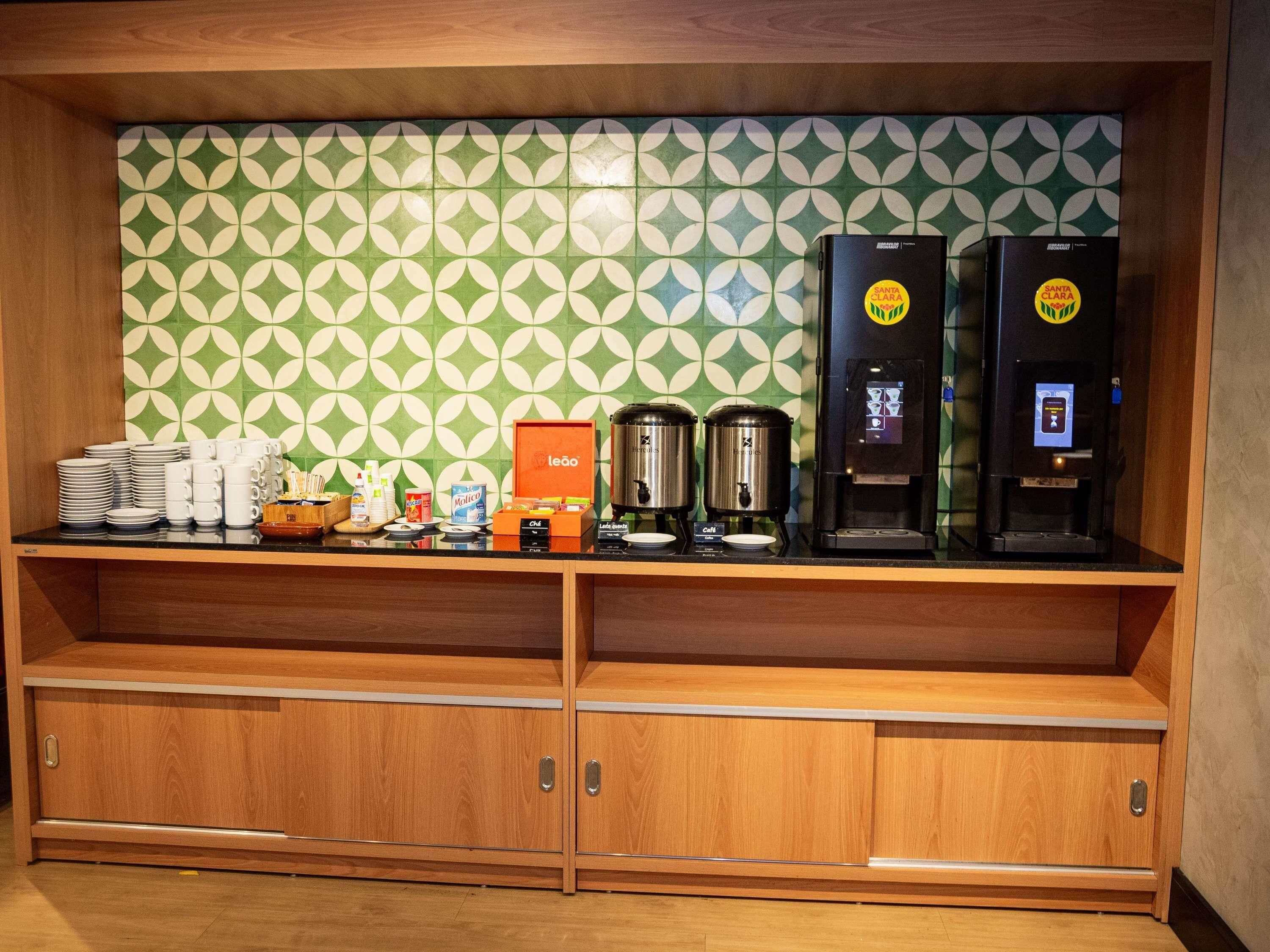 A breakfast bar with coffee machines, a selection of mugs, and a 'leao' branded box.