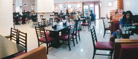 A spacious restaurant with high ceilings, multiple tables and chairs, and a bright, well-lit interior.