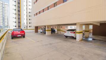Un aparcamiento de varios niveles con varios coches estacionados, suelos de hormigón y líneas de seguridad amarillas.