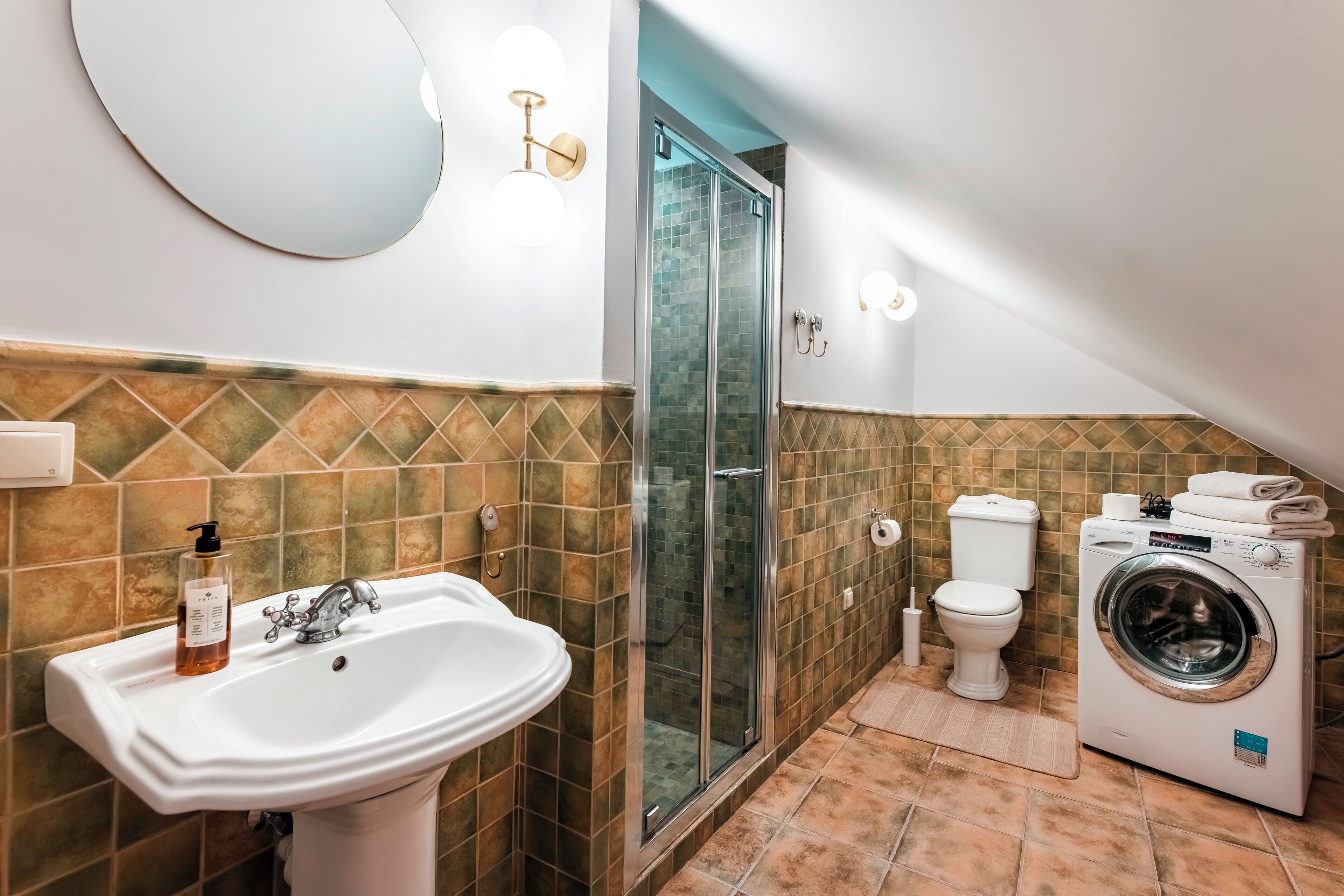 Un baño con lavamanos, inodoro, ducha y lavadora.