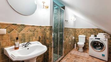 Un baño con lavamanos, inodoro, ducha y lavadora.