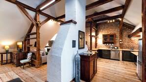 Een loftachtige kamer met zichtbare houten balken, een bakstenen muur en een houten vloer.