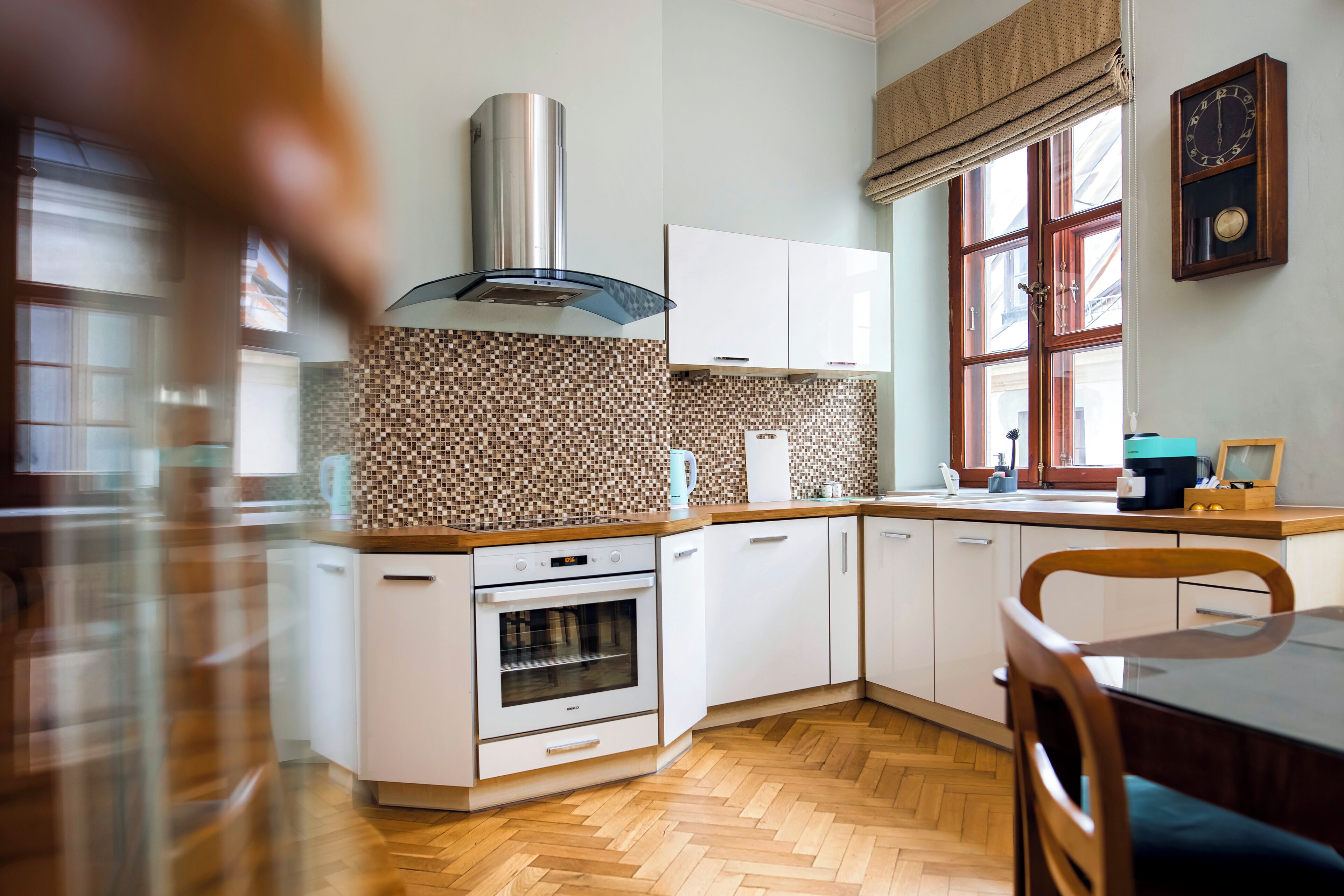 Une cuisine moderne avec des armoires blanches, une hotte de cuisinière en acier inoxydable et un dosseret décoré d’un motif en chevrons.