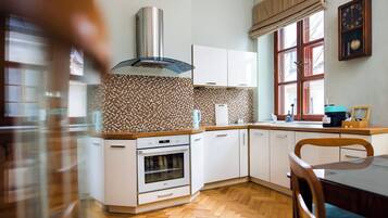 Une cuisine moderne avec des armoires blanches, une hotte de cuisinière en acier inoxydable et un dosseret décoré d’un motif en chevrons.