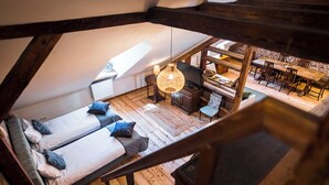 Een slaapkamer in zolderstijl met een houten vloer, twee bedden, een televisie en een eethoek met houten meubels.