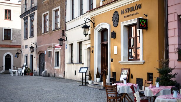 Een geplaveid straatje met terras van een restaurant genaamd '16 Stolów'.