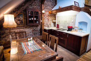 A rustic kitchen with a wooden table, chairs, and a tiled backsplash.