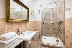 A bathroom with a sink, mirror, and shower.