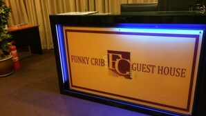 Un comptoir d’accueil avec une pancarte indiquant : « Funky Crib Guest House ».