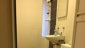 Une petite salle de bain propre, équipée de toilettes, d’un lavabo et d’un miroir.