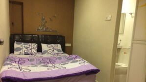 Une chambre à coucher avec un lit, une tête de lit et un luminaire fixé au mur.
