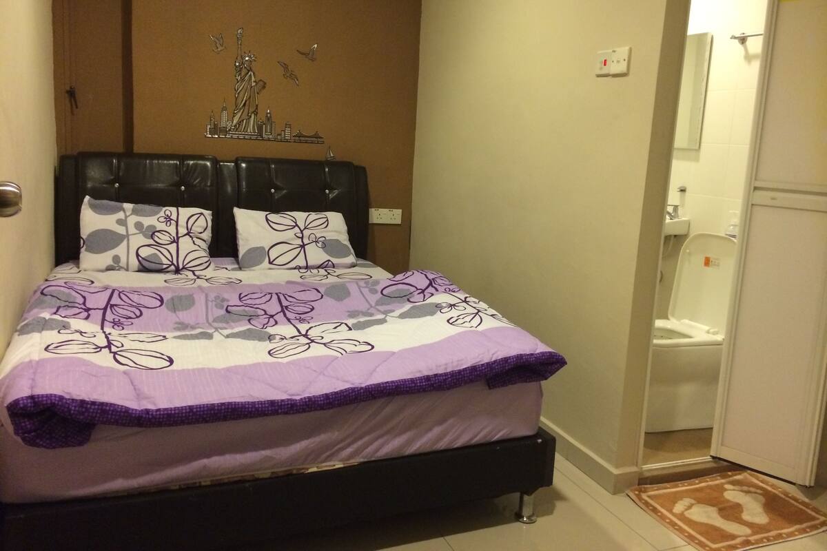 A bedroom with a bed, a headboard, and a wall-mounted light fixture.