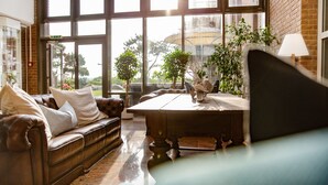 A cozy living room with a leather sofa, a wooden coffee table, and potted plants. - Stadthotel Eckernförde (Eckernfoerde)