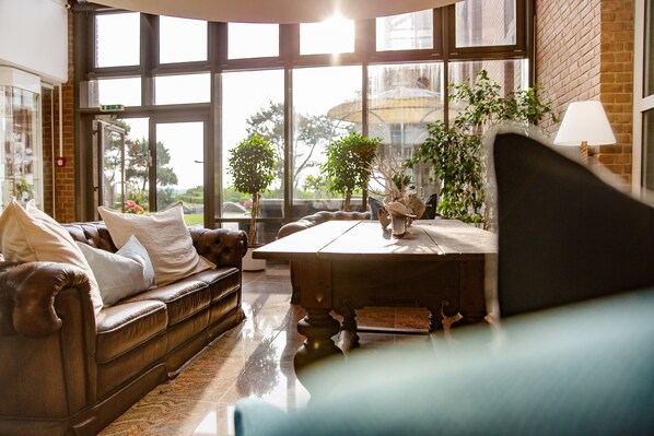 A cozy living room with a leather sofa, a wooden coffee table, and potted plants.