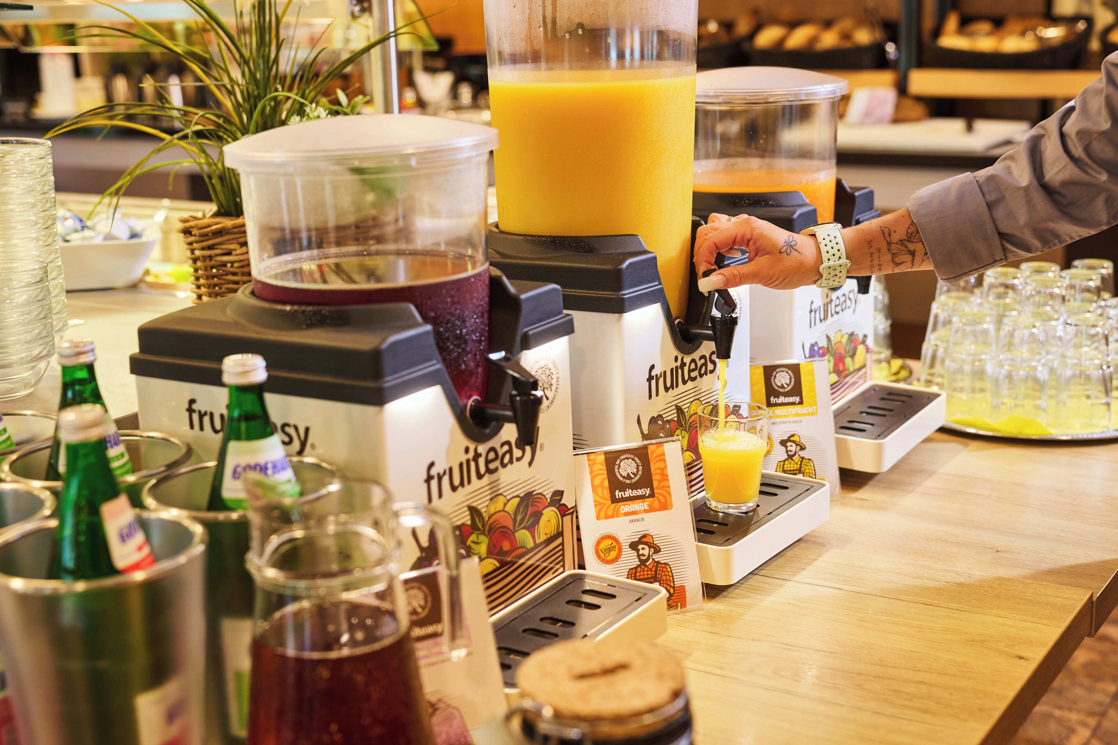 A juice bar with a blender, bottles, and juice dispensers.