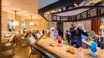 A bar area with wicker furniture, a bar counter, and a variety of bottles and glasses.