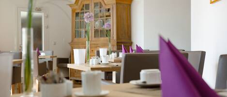 A dining area with a wooden cabinet, white tableware, and purple napkins.