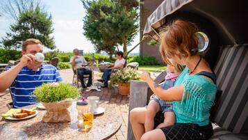 A patio area with round tables, outdoor seating, and potted plants.