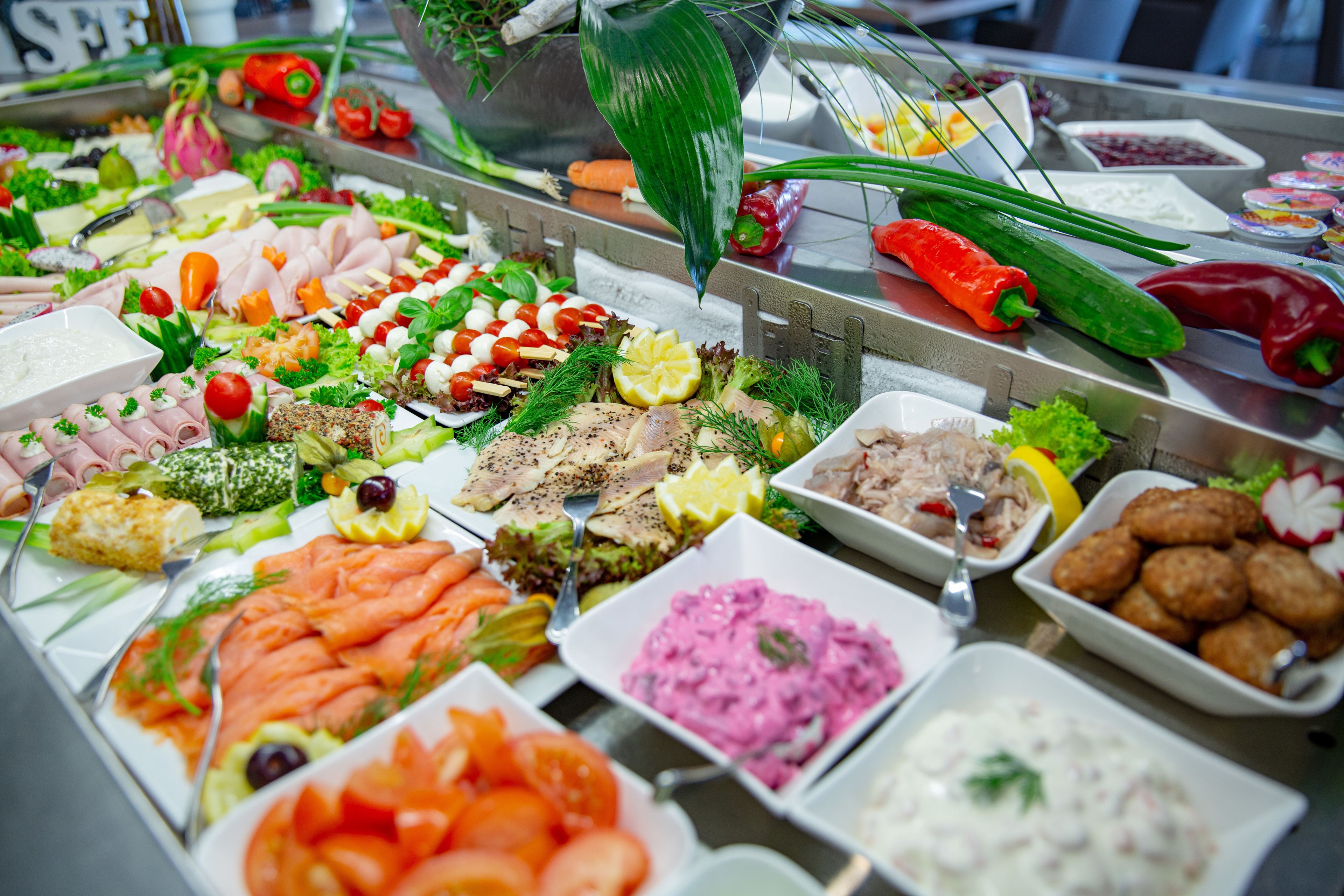 Ein Buffet mit verschiedenen Speisen, darunter Fleisch, Käse und Gemüse.