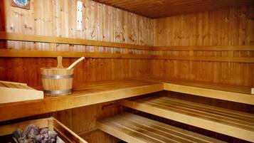 Una sauna de madera con bancos y un cubo con una cuchara.