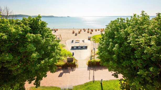 A beach with sun loungers and a paved area with benches. - Stadthotel Eckernförde (Eckernfoerde)