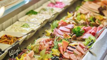 Ein reichhaltiges Buffet mit verschiedenen Speisen, darunter Fleisch, Salate und Obst.
