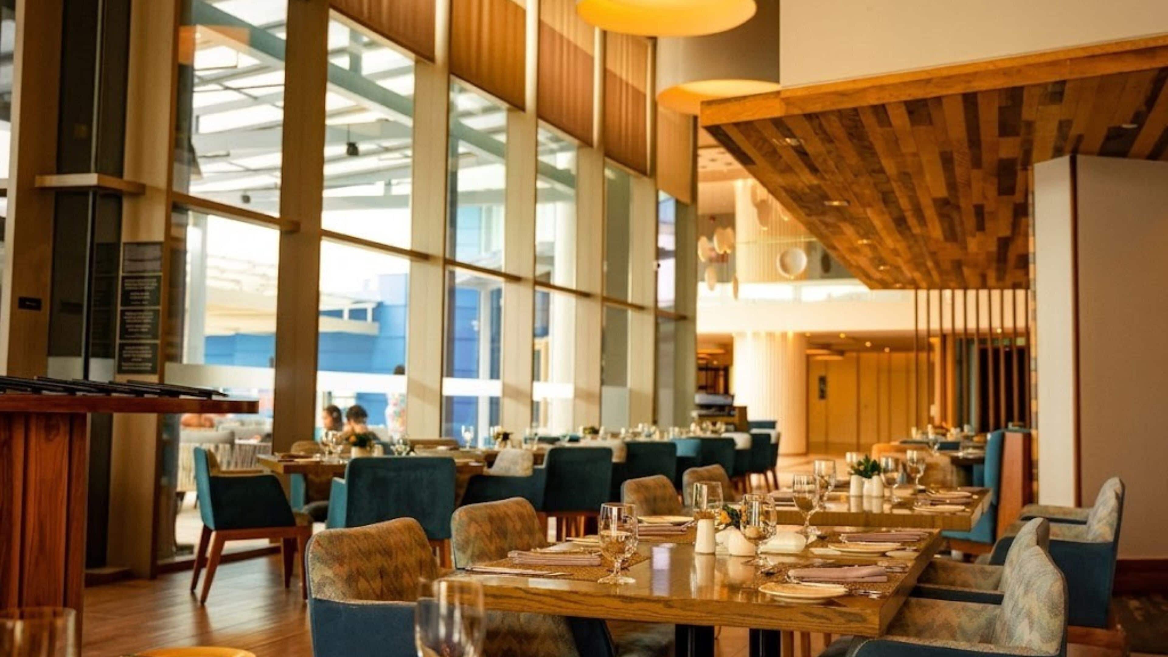 Ein geräumiges Restaurant mit hohen Decken, großen Fenstern und einem modernen Interieur.