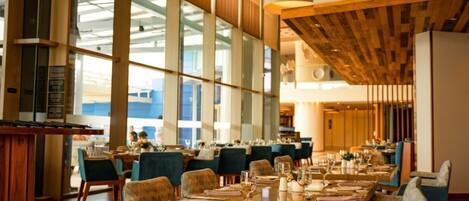 Ein geräumiges Restaurant mit hohen Decken, großen Fenstern und einem modernen Interieur.