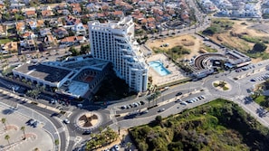 Stunning hotel complex with a unique, curved facade, featuring a swimming pool and parking area.