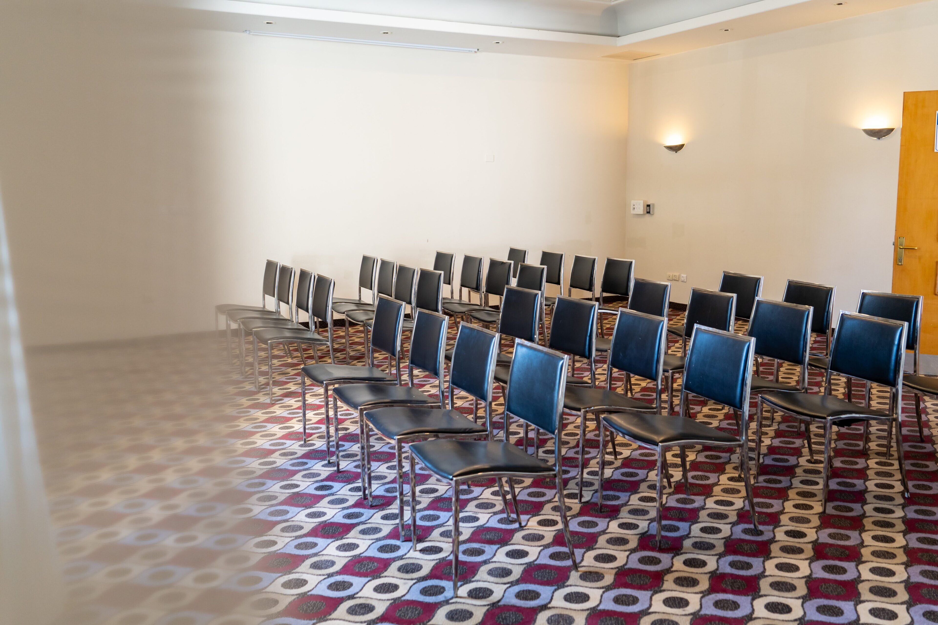 Un salón de conferencias con filas de sillas y una alfombra estampada.