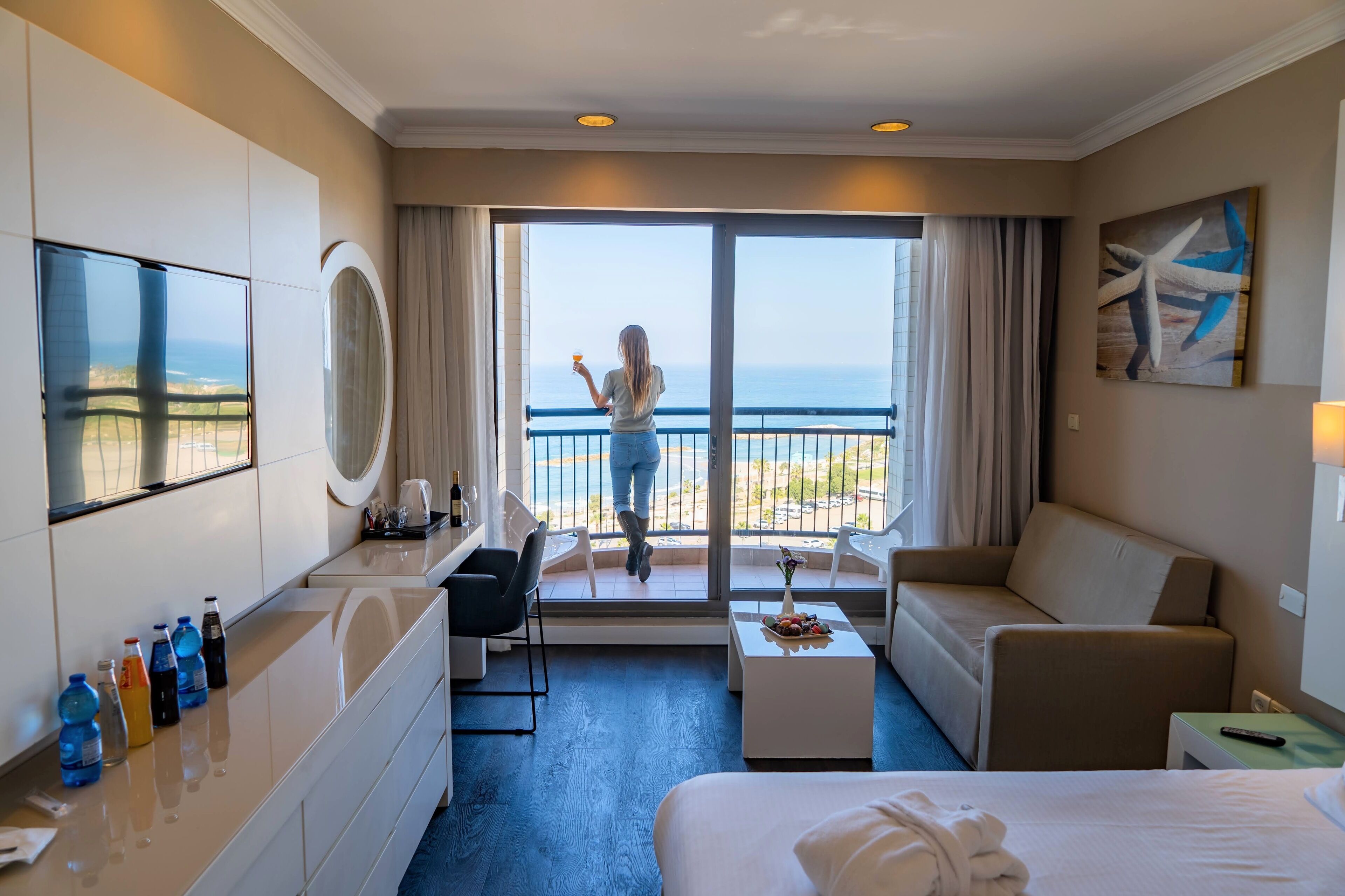 Een hotelkamer met balkon, een bed, een slaapbank, een bureau en een televisie.