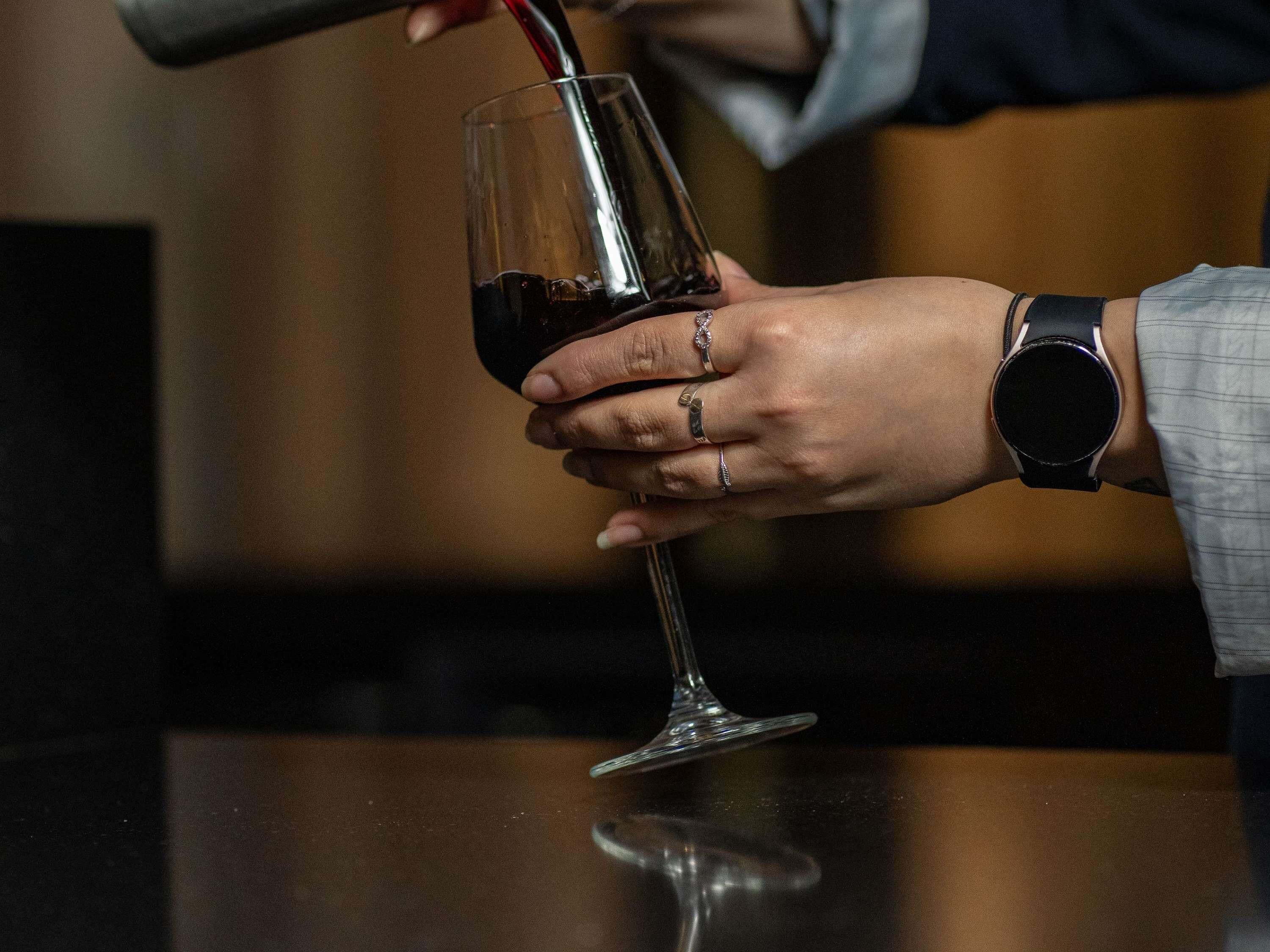 Une personne tenant un verre de vin et portant une montre au poignet.