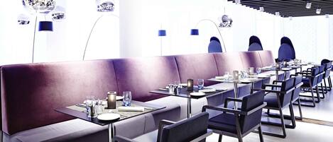 Un restaurant moderne doté d’un long comptoir, de banquettes violettes et de luminaires suspendus sphériques originaux.