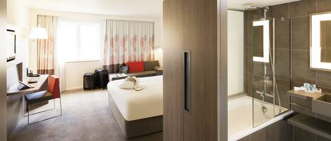 Une chambre d’hôtel équipée d’un lit, d’un bureau, d’une chaise et d’un espace douche.