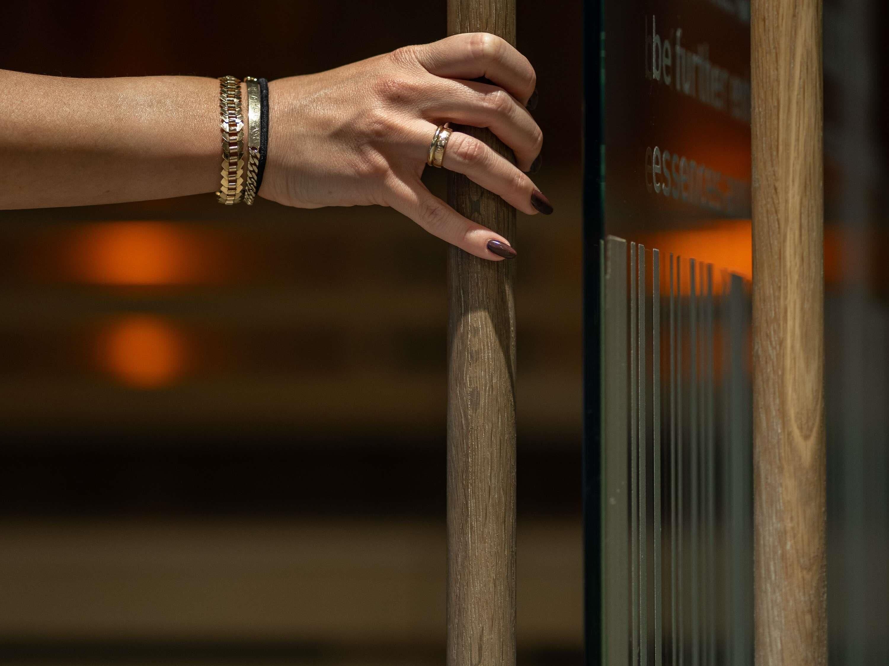 A hand resting on a wooden post with a glass panel displaying text.