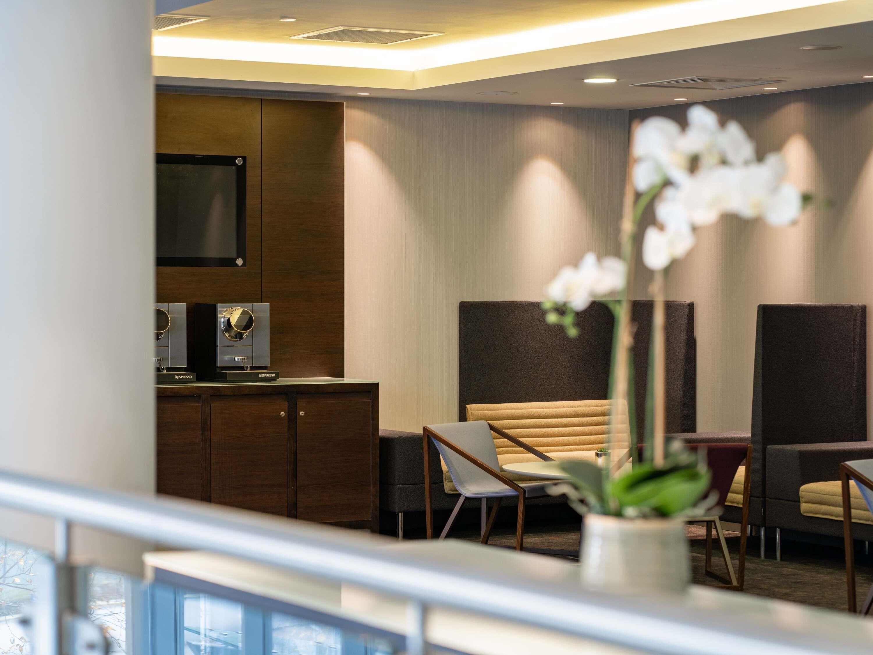 A hotel lobby with a reception desk, seating area, and a large screen.