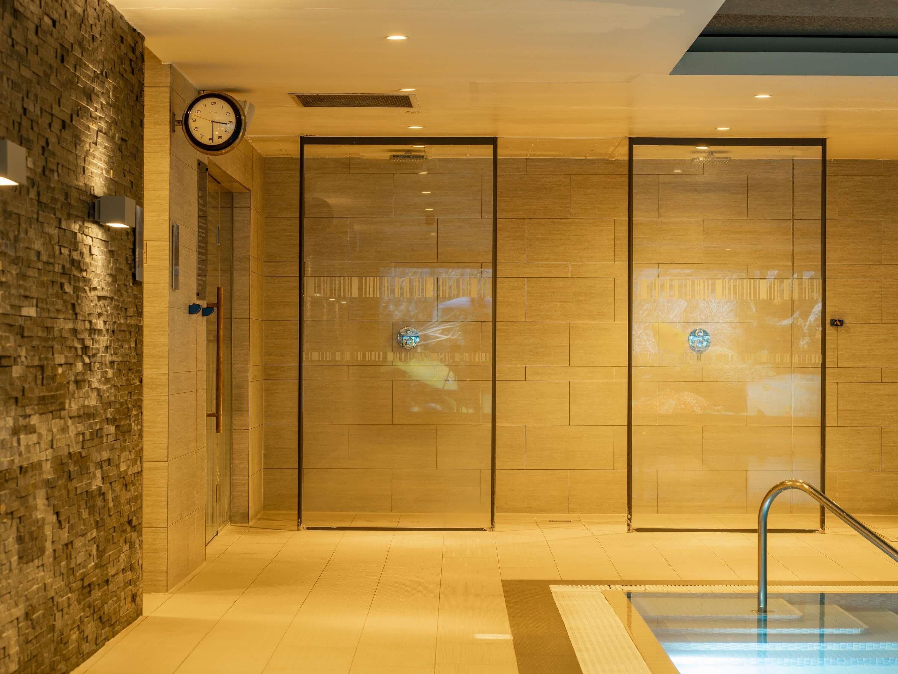 A hotel lobby with a clock, a pool area, and a wall with a textured pattern.