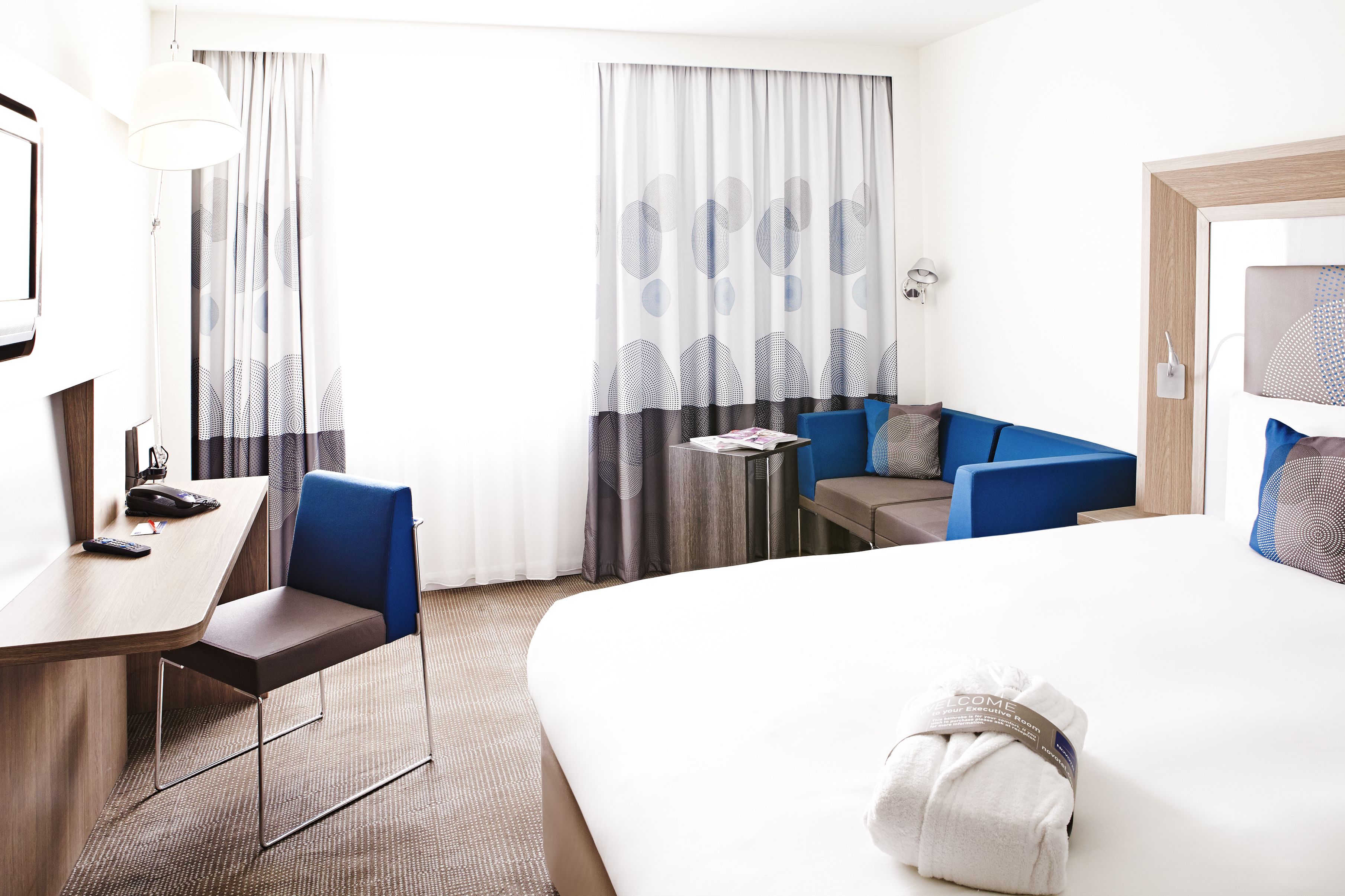 Een hotelkamer met een bed, een bureau met stoel, een klein tafeltje en een bank.