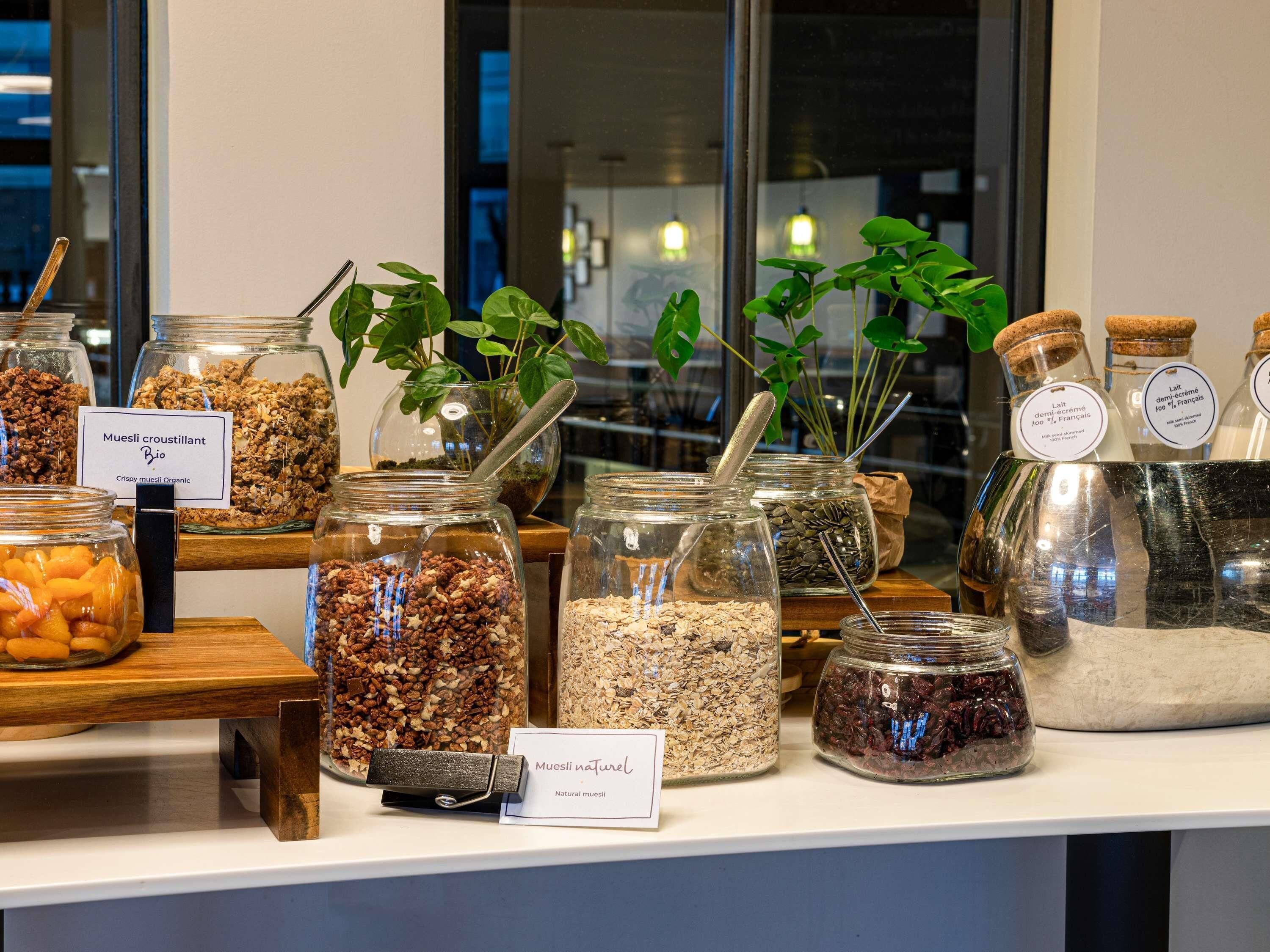 A variety of food items displayed in glass jars on a counter, including organic muesli and dried fruits.
