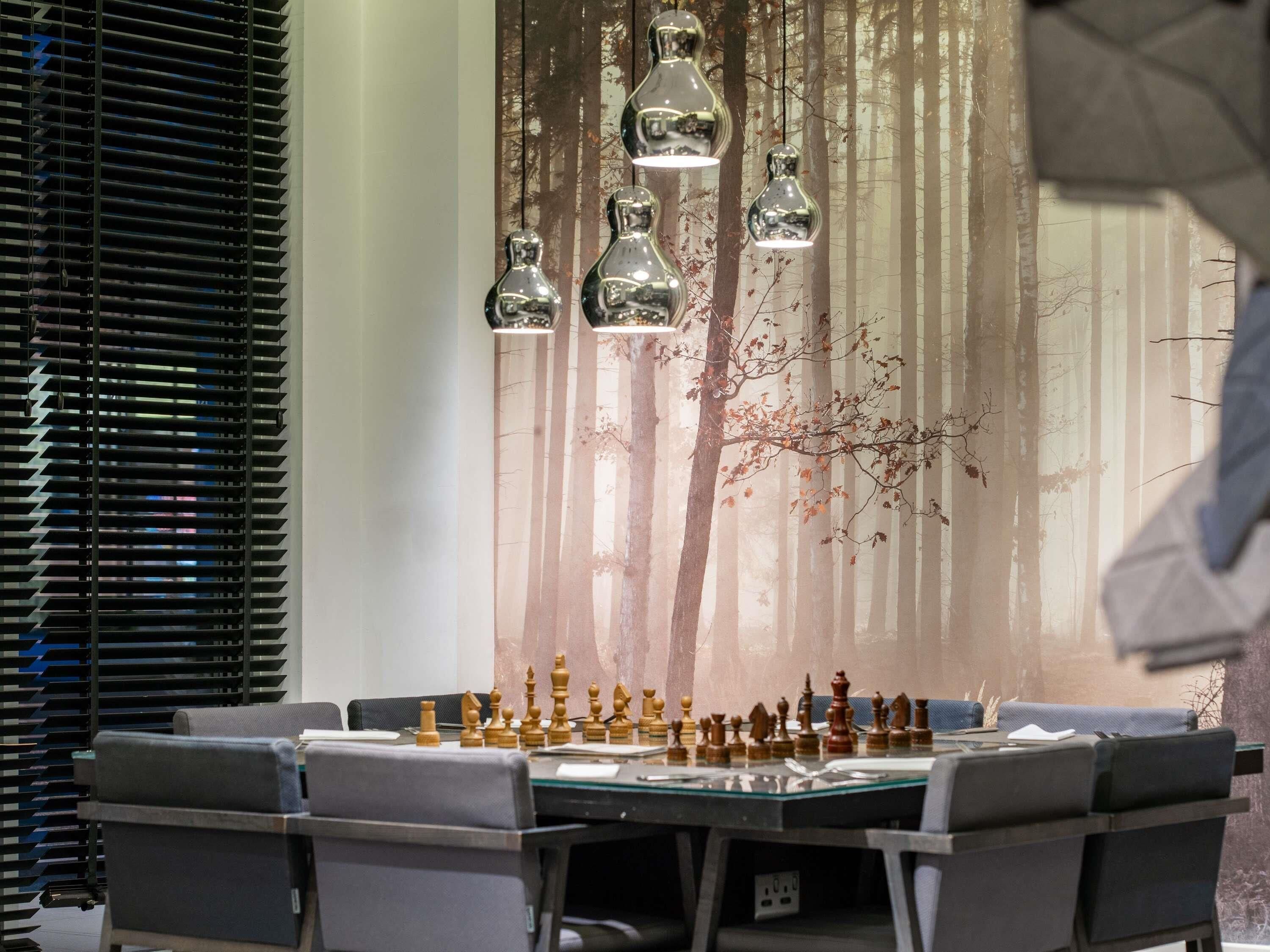 Un coin repas avec un jeu d’échecs posé sur une table en verre, entourée de chaises.