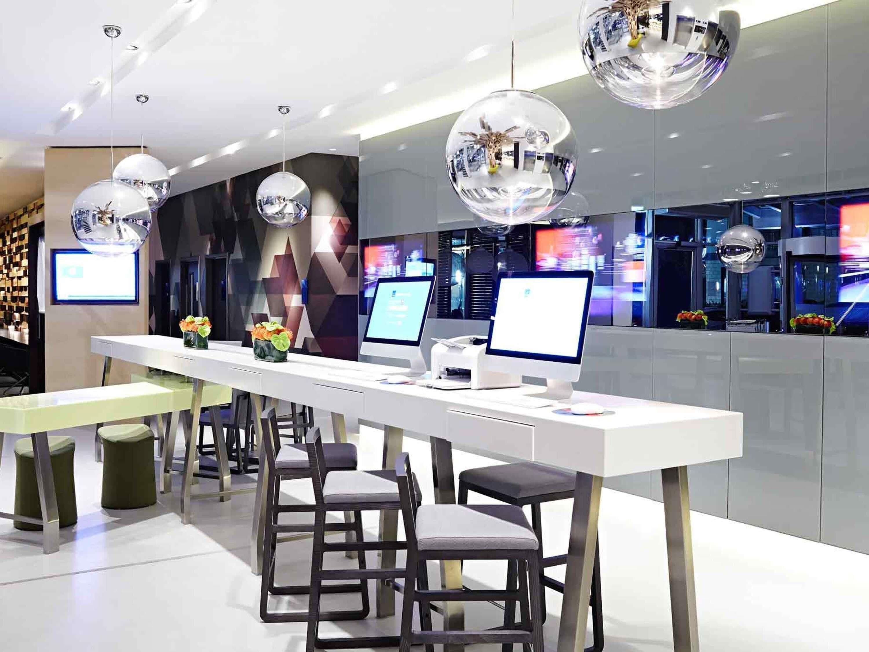 A modern reception area with a long counter, two computer monitors, and a decorative mirror.